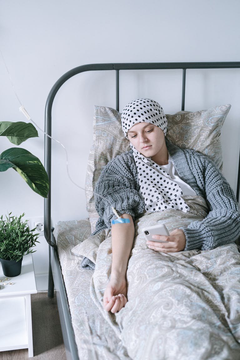 Woman in Gray and White Polka Dot Robe Sitting on Bed